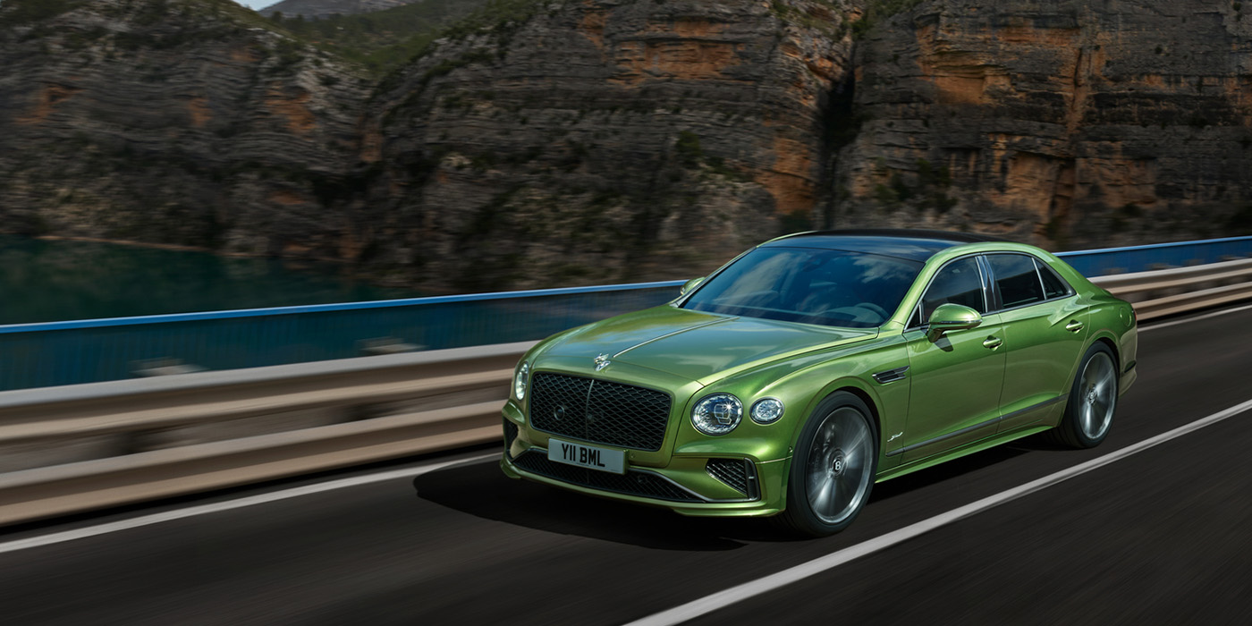 Bentley Geneve Bentley New Flying Spur Speed v8 hybrid sedan driving dynamically on a mountain road in Tourmaline Green paint