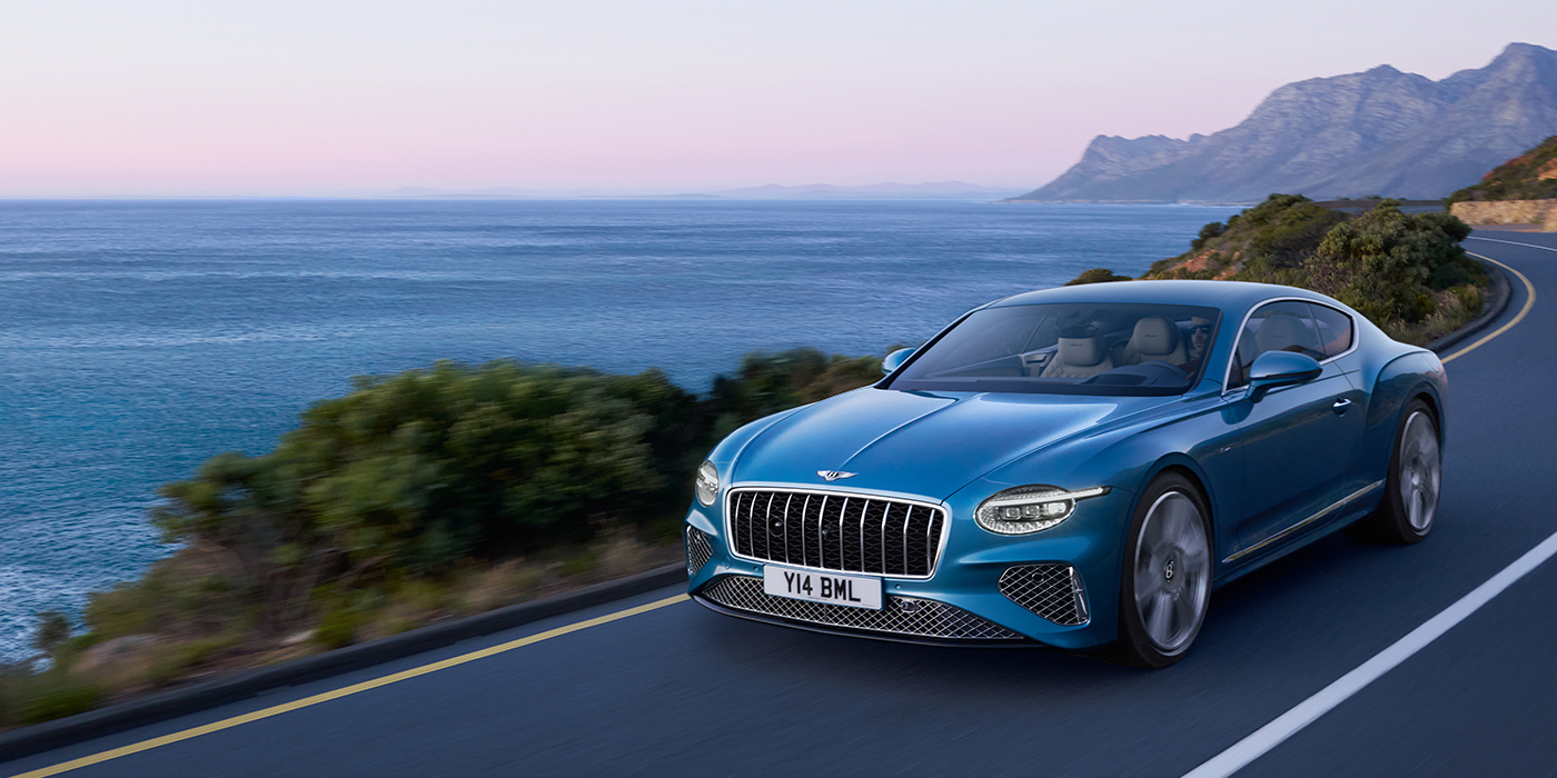 Bentley Geneve New Bentley Continental GT Azure coupe in Light Windsor blue paint with 22 inch Azure wheels and chrome grill, driving dynamically by the sea