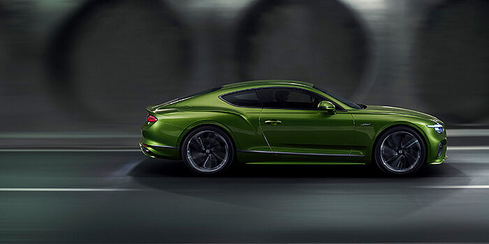  Bentley Geneve Bentley Continental GT coupe in Tourmaline Green paint driving in profile on a dark road