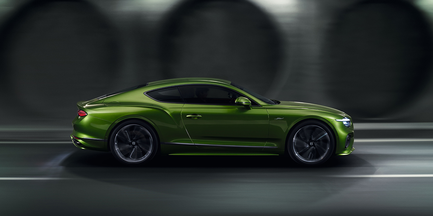 Bentley Geneve Bentley Continental GT coupe in Tourmaline Green paint driving in profile on a dark road