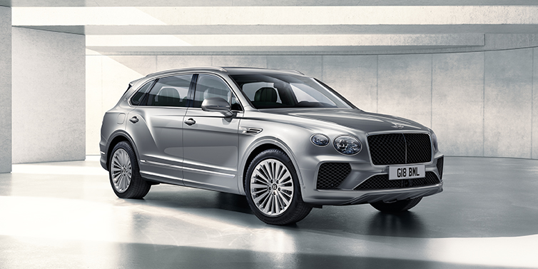 Bentley Geneve Bentley Bentayga Extended Wheelbase SUV front three quarter in Moonbeam paint with a grey background